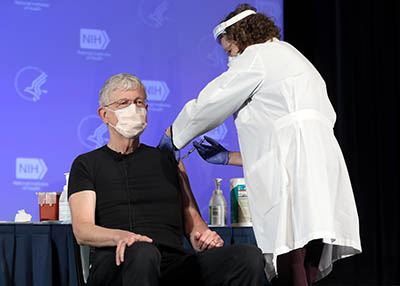 Francis Collins receiving a vaccine injection from a health care worker