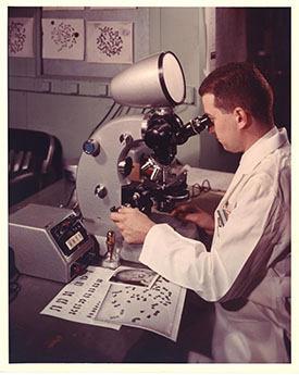 scientist in white lab coat looking into a microscope