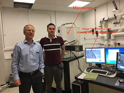 Richard Leapman and Matt Guay standing in front of the powerful microscope.