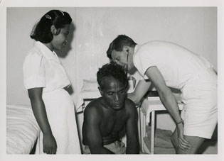 Ed Rall examining a male patient while a nurse looks on