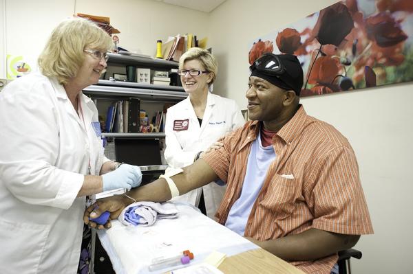 black man getting blood drawn by nurses