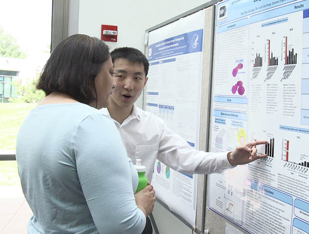 Two students discuss a scientific poster