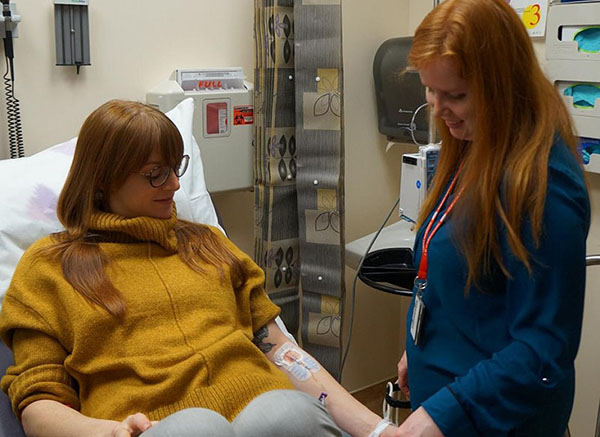 NIAID Research Nurse Jennifer Cunningham, B.S.N., looks on as a healthy volunteer receives an infusion of CIS43LS, an experimental monoclonal antibody against malaria, as part of a Phase 1 clinical trial.