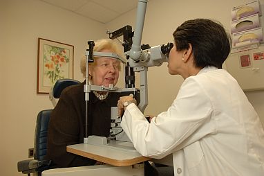 Dr. Emily Chew, deputy director of the NEI Division of Epidemiology and Clinical Applications, gives a female patient an eye exam.
