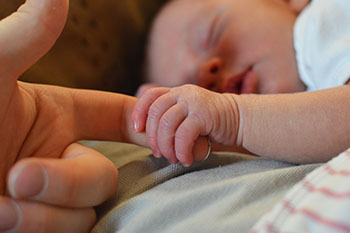 baby holding an adult's finger