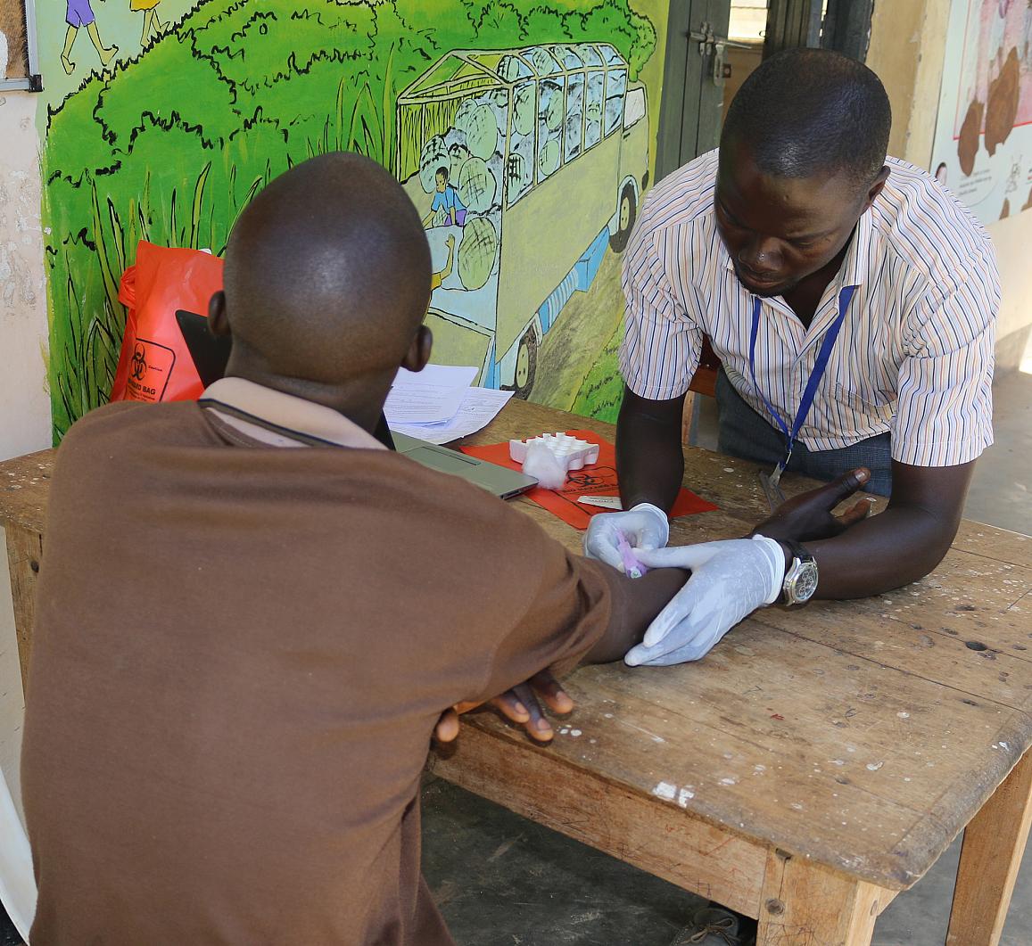 A research assistant draws blood for HIV testing from a participant in the Rakai Community Cohort Study.