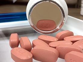 pink oval pills on a tray, having spilled out of a pill bottle
