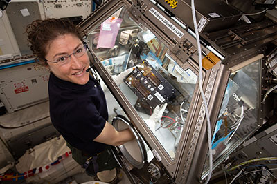 Female astronaut at a scientific workstation aboard the International Space Station