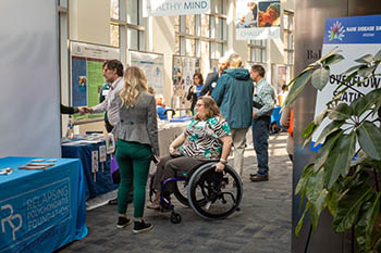 people looking at exhibits; one woman is in a wheelchair