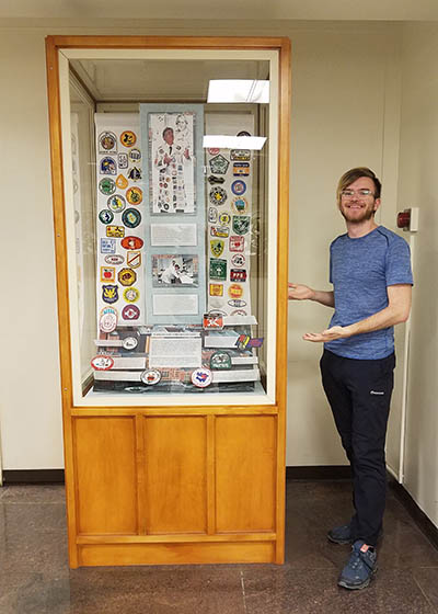 exhibit case with patches; person standing next to it