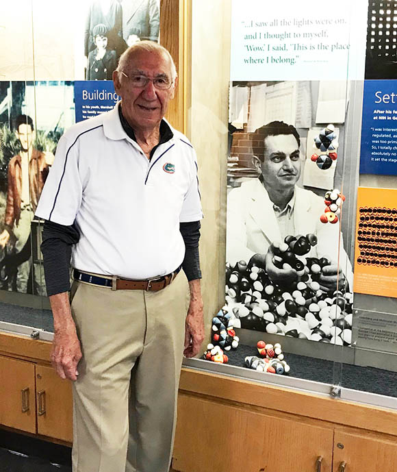 David Aronson standing next to life-size photo of Marshall Nirenberg