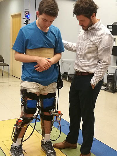 a boy wearing the leg exoskeleton and the scientist conducting the study