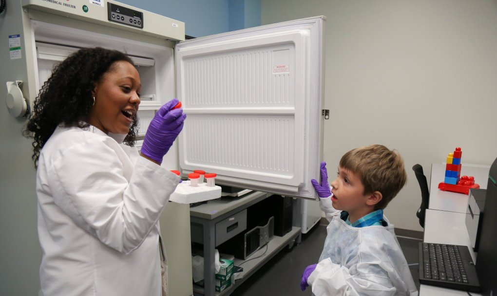 Bioinformatician Keri Richards shows 7-year-old James vials from a freezer in her lab at NIDCD. The vials contain DNA samples.