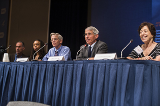 five people sitting at panel discussion table facing audience