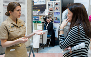  WOMAN EXPLAINING HER POSTER TO ANOTHER WOMAN