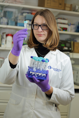 Jacqueline Mays looking at a test tube.