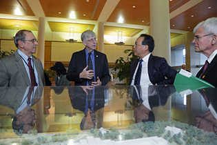 Four men standing at the model of the NIH Clinical Center.