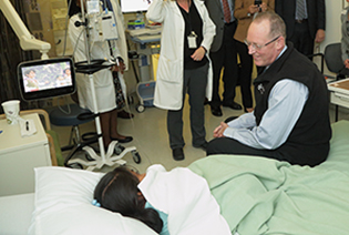 Paul Farmer sitting on end of bed with young patient
