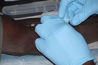 hands wearing blue gloves administering an injection