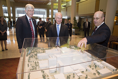  Three men standing at the glassed-in scale model of the NIH Clinical Center