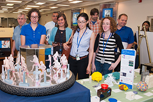 People gathered round objects made by 3-D printers and more.