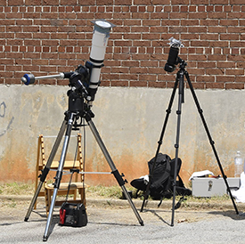 cameras on tripods; one has a telescope lens attached covered by a Mylar filter, the other a Mylar filter.