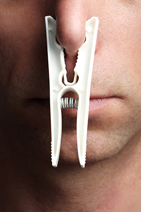 MAN'S NOSE WITH A CLOTHESPIN HOLDING IT SHUT