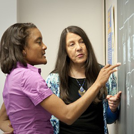 two women talking at a chalkboard