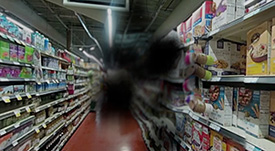aisle in a grocery store; view is blocked by a black smudge in the middle of the frame.
