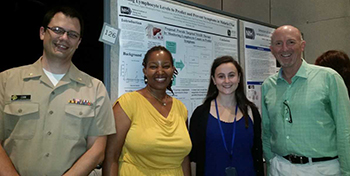 Four people standing next to a poster