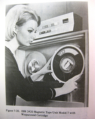 A woman standing in front of a unit containing the old computer tape reels
