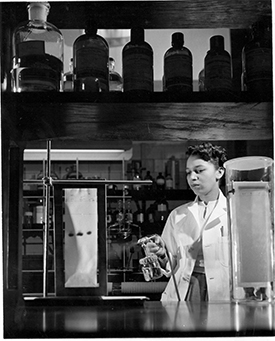 alma levant hayden spraying reagent out of a spray bottle onto vertically held sheet of paper with marks on it.