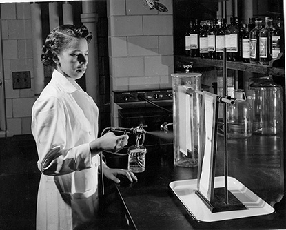 Alma Levant Hayden in the lab spraying paper with a reagent