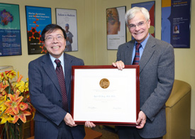 Kuan Teh-Jeang and Michael Gottesman holding a large framed certificate