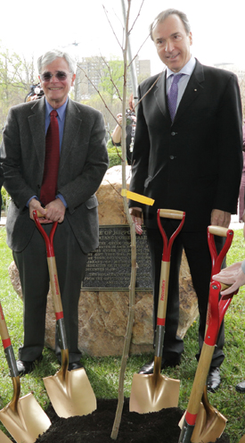 Michael Gottesman and the Greek Ambassador standing with shovels next to the tree