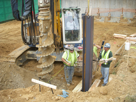 TWO CONSTRUCTION WORKERS WITH GIANT DRILL THAT'S TALLER THAN THEM