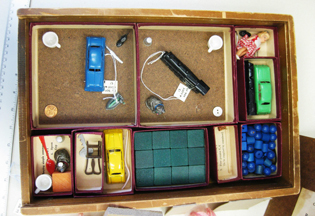 Flat box with compartments with toy cars, blocks, and other items