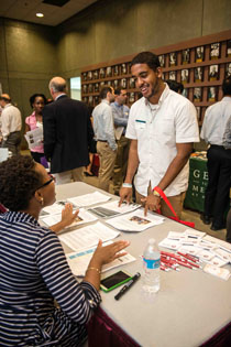 Felix Contreras standing at a table talking to recruiters