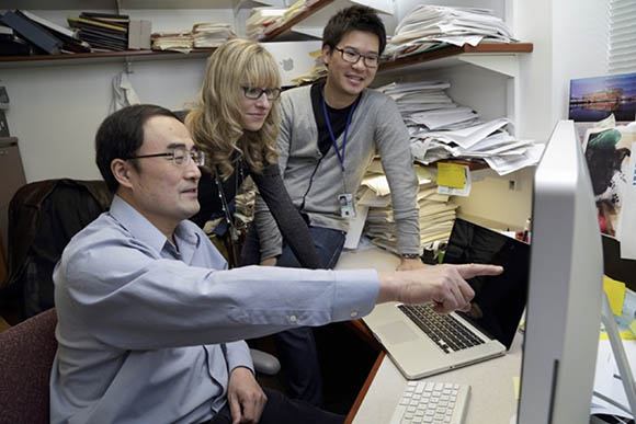 Scientists in a lab looking at computer screen.