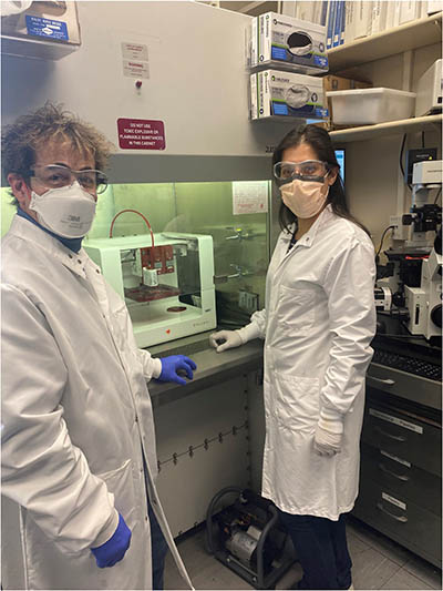 Two people next to a bioprinter.