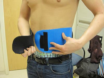 person putting on a blue spleen guard (looks like a wide belt)