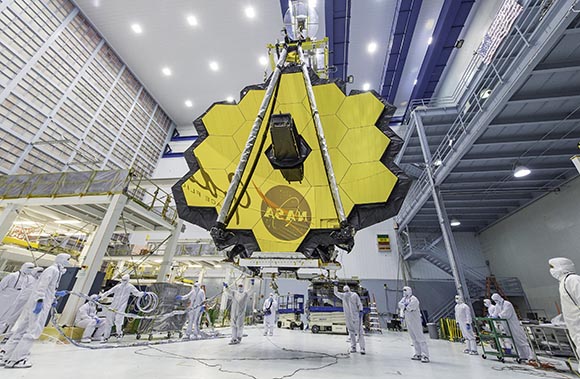 giant mirror made up of yellow hexagonal shapes being lifted by a crane