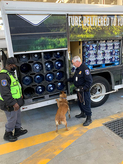 policeman, dog, and security guard inspecting a truck