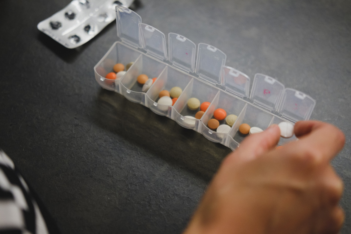 person sorting medications in a pill organizer