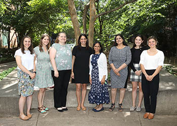 8 women standing under a tree