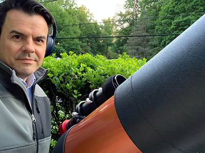 man wearing headphones next to a telescope