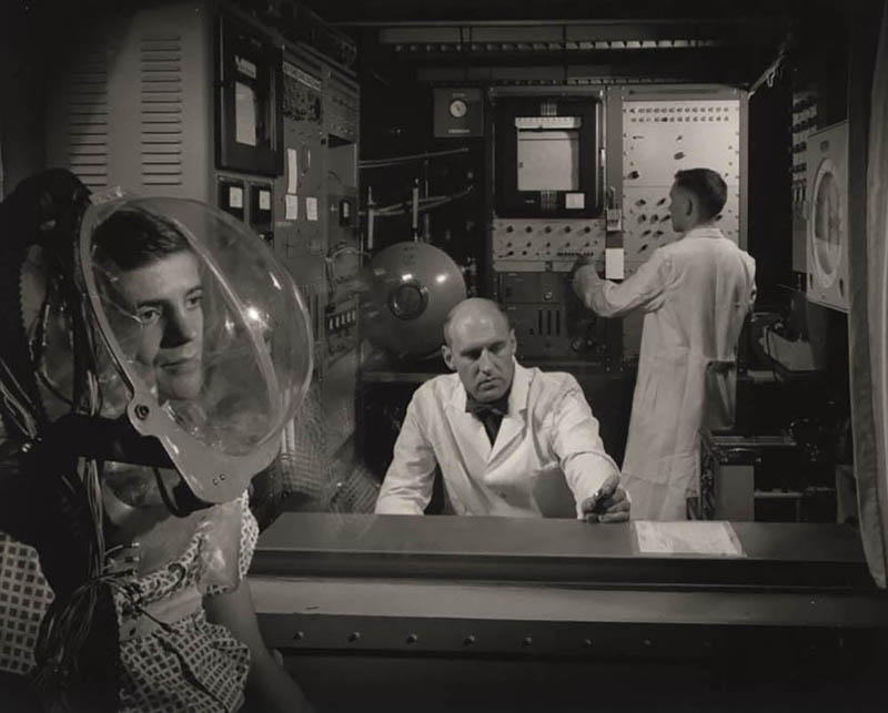 man wearing a hood to collect data on oxygen consumption while scientists monitor him