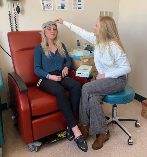 A member of Dr. Gluck’s research team practices setting up the transcranial direct current stimulation (tDCS) equipment on Emma Stinson (left), the new study’s first author