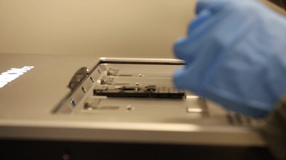 a scientist loading a sample into a DNA sequencing machine