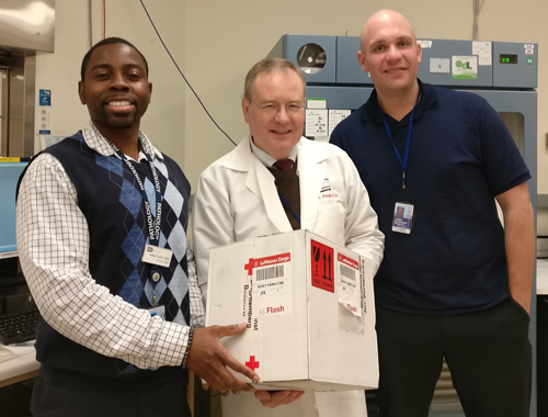 Dr. Willy Flegel (center) and two of his DTM colleagues receive a package of blood with a rare type sent all the way from Germany